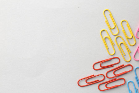 Colorful paper clips on light background, flat lay. Space for textの写真素材