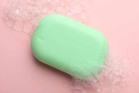 Soap bar with foam on light pink backgroundの写真素材