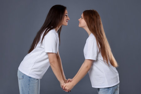 Beautiful mother with teenage daughter on grey backgroundの写真素材