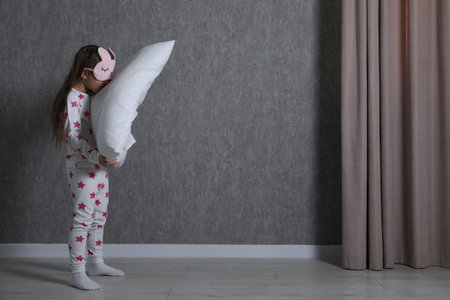 Little girl with pillow suffering from sleepwalking at home, space for textの写真素材