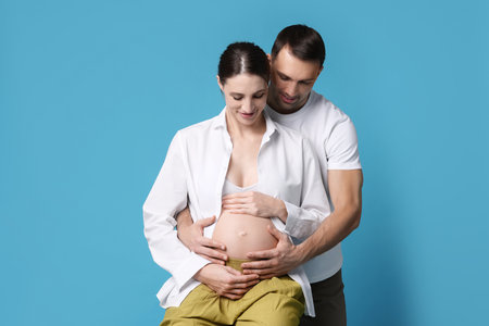 Pregnant woman and her husband on blue backgroundの写真素材