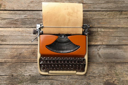 Vintage typewriter with sheet of parchment paper on wooden table, top viewの写真素材