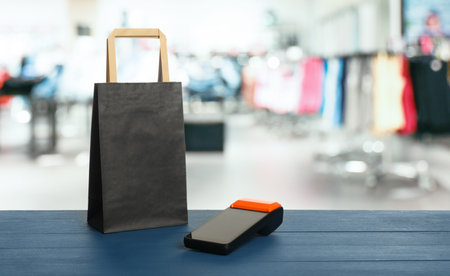 Payment terminal and shopping bag on blue wooden counter in clothes storeの写真素材