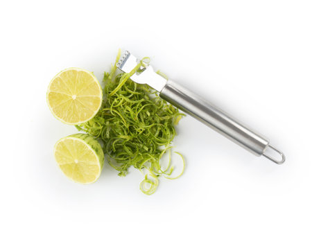 Lime zest, fresh fruits and zester tool isolated on white, top view