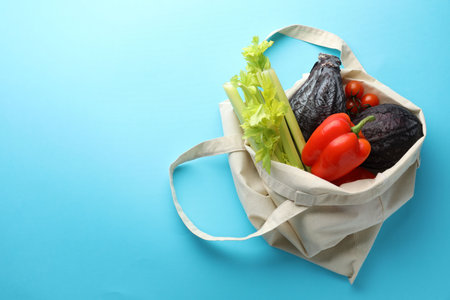 Eco bag with different vegetables on light blue background, top view. Space for textの写真素材