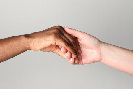 Stop racism. People of different skin colors holding hands on light grey background, closeupの写真素材