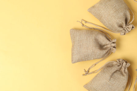 Natural burlap bags on yellow background, flat lay. Space for textの写真素材