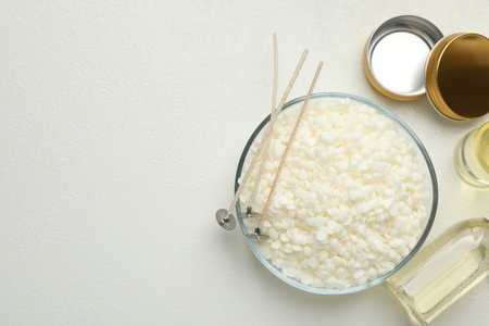 Soy wax and other supplies for making candles on white table, flat lay. Space for textの写真素材