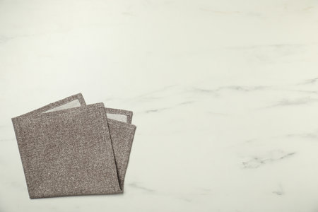 Gray napkin on white marble table, top view. Space for text