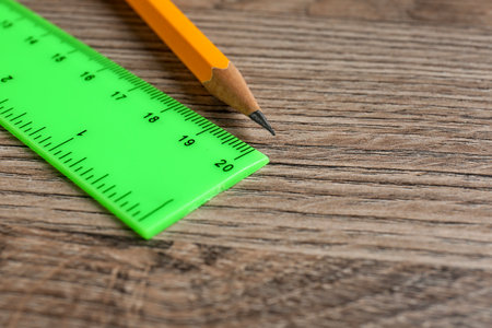 Green ruler and pencil on wooden table, closeup. Space for textの写真素材