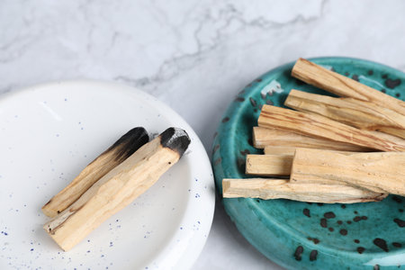 Whole and burnt palo santo sticks on white marble table, closeupの写真素材