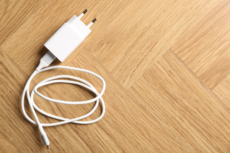 USB power adapter with charge cable on wooden table, top view. Space for textの写真素材