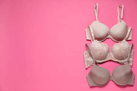 Beautiful bras on pink background, flat lay. Space for textの写真素材