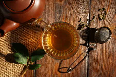 Refreshing green tea in cup, strainer and leaves on wooden table, flat layの写真素材