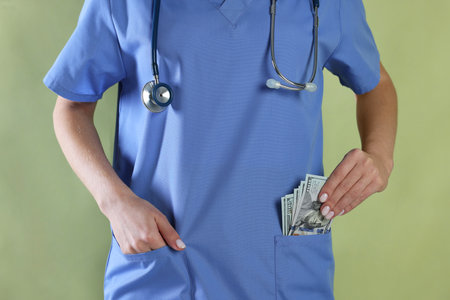 Doctor putting dollar banknotes into her pocket on green background, closeup
