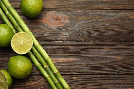 Fresh limes and bamboo stems on wooden table, flat lay. Space for textの写真素材