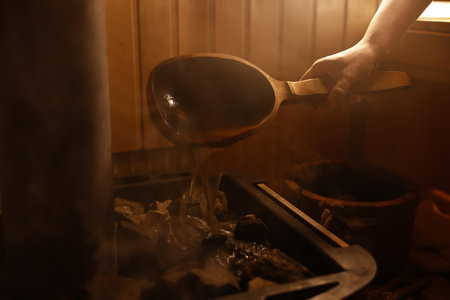 Woman pouring water on stones in sauna, closeupの写真素材