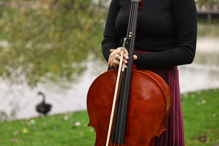 Woman with cello in park, closeup. Space for text