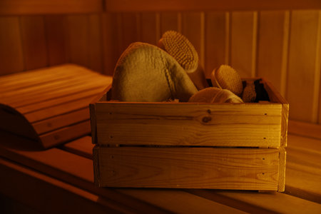 Crate with bath accessories on bench in saunaの写真素材