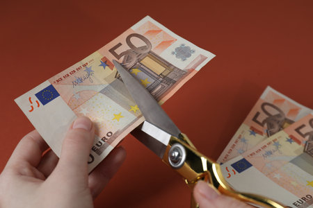 Woman cutting euro banknotes on brown background, closeupの写真素材