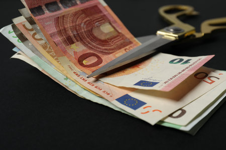 Euro banknotes and scissors on black background, closeupの写真素材