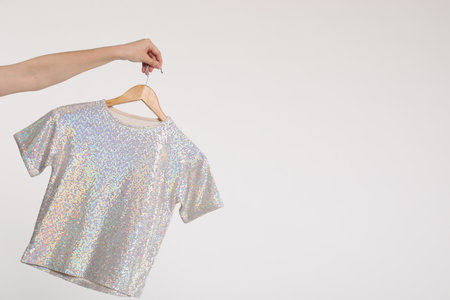 Woman holding hanger with t-shirt on white background, closeup