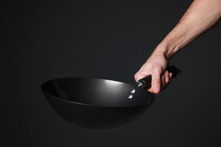 Chef holding frying pan on black background, closeupの写真素材