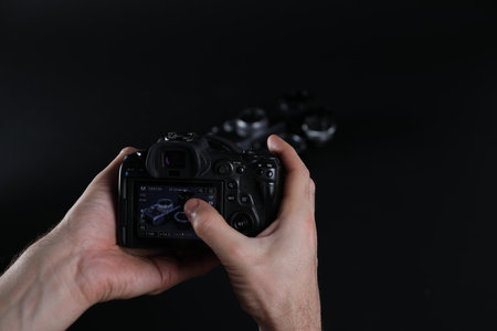 Photographer taking photo with professional camera on dark background, closeupの写真素材