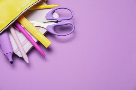 Pencil case with different stationery on purple background, flat lay. Space for textの写真素材