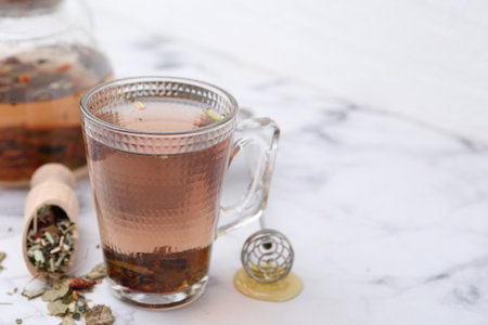 Delicious herbal tea with honey and dry leaves on white marble table, closeup. Space for textの写真素材