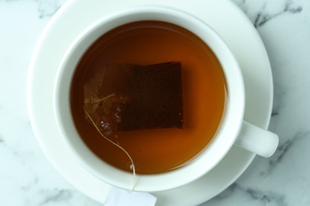 Tea bag in cup with hot drink on light marble table, top viewの写真素材