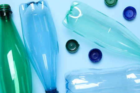 Empty plastic bottles on light blue background, flat lay