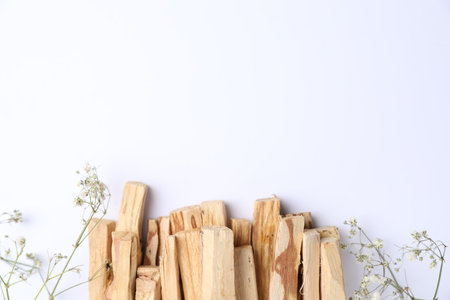 Palo santo sticks and gypsophila flowers on white background, flat lay. Space for textの写真素材