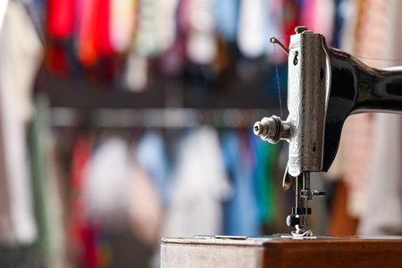Vintage sewing machine with thread on blurred background, closeup. Space for textの写真素材