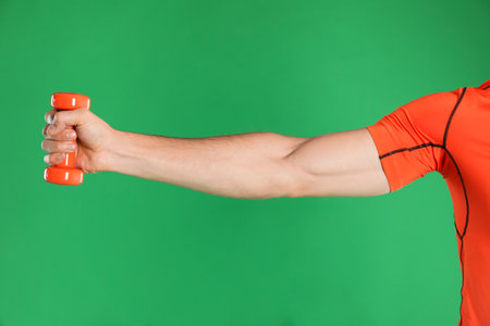 Man exercising with dumbbell on green background, closeupの写真素材