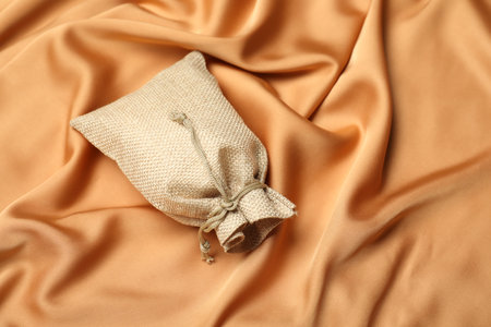 Beige burlap sack on orange fabric, above view. Space for textの写真素材