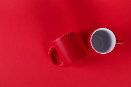 Two blank mugs on red background, top view. Mockup for design