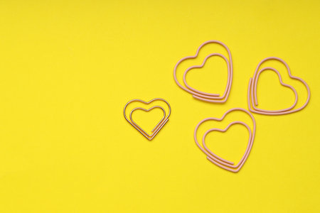Heart shaped paper clips on yellow background, flat lay. Space for textの写真素材