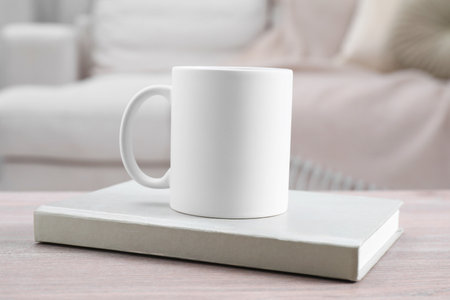 Blank ceramic mug and notebook on wooden table. Mockup for designの写真素材