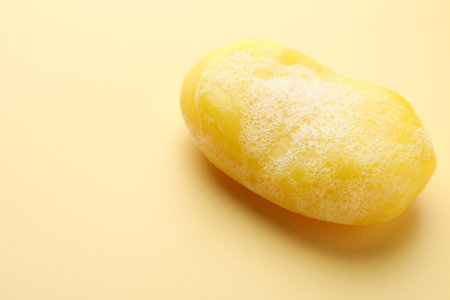 Soap bar with foam on yellow background, closeup. Space for textの写真素材