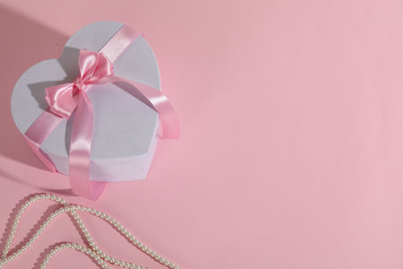 Beautiful wedding gift and pearl jewelry on pink background, flat lay. Space for textの写真素材