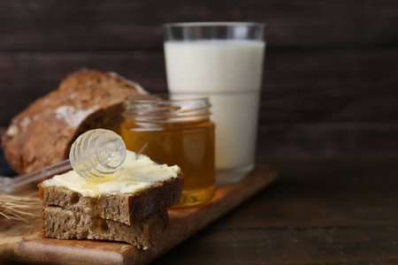 Tasty sandwich with butter, honey, and milk on wooden table, closeup. Space for textの写真素材
