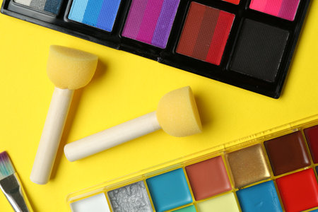 Face paints and tools on yellow background, flat layの写真素材