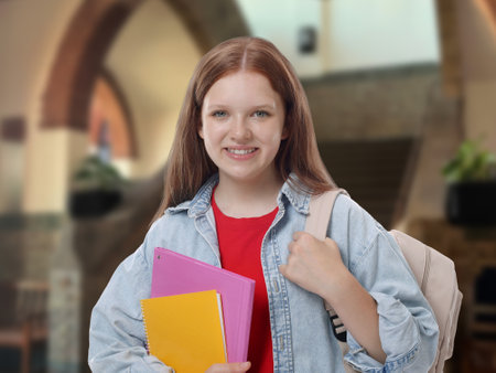 Teenage student with notebooks and backpack in college