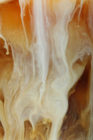 Refreshing coffee with ice and milk as background, closeup