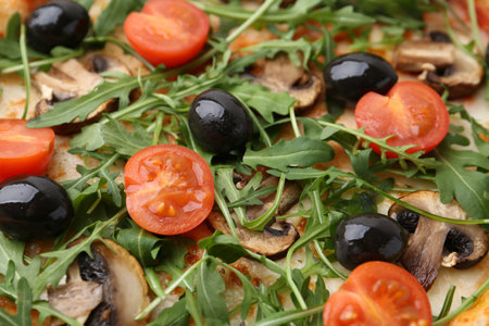 Tasty pizza with cherry tomatoes, black olives, mushrooms and arugula as background, closeupの写真素材