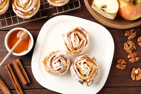 Tasty apple roses with powdered sugar served on wooden table, flat layの写真素材