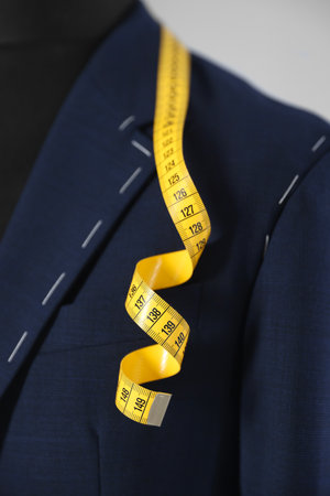 Semi-ready jacket and measuring tape on mannequin against gray background, closeupの写真素材