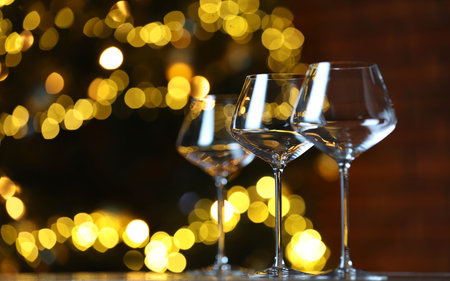 Wine glasses on table against blurred lights, space for text. Bokeh effectの写真素材