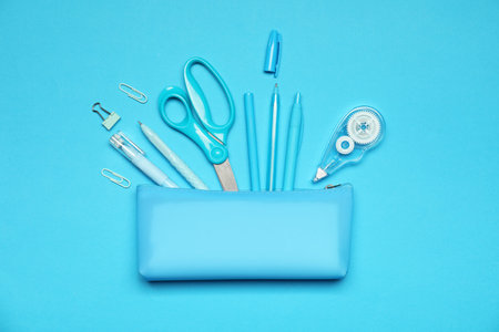 Pencil case and different stationery on light blue background, flat layの写真素材